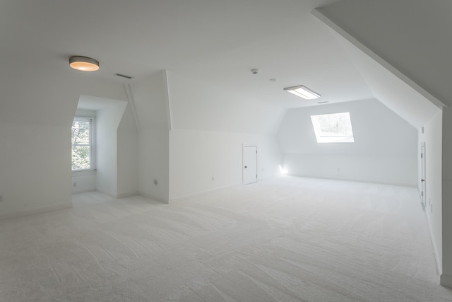 bonus room with light carpet, vaulted ceiling with skylight, and plenty of natural light