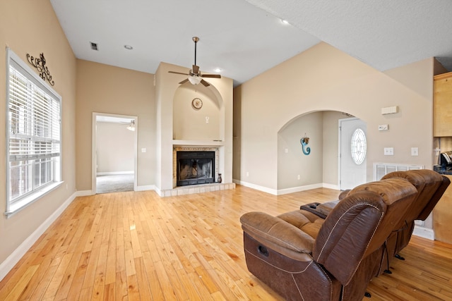 living room featuring a wealth of natural light, a tile fireplace, and light hardwood / wood-style flooring