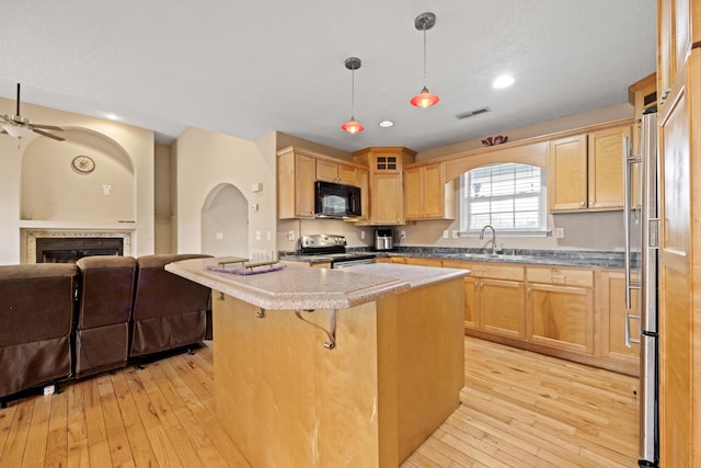 kitchen featuring stainless steel appliances, a kitchen island, pendant lighting, a breakfast bar area, and light hardwood / wood-style flooring