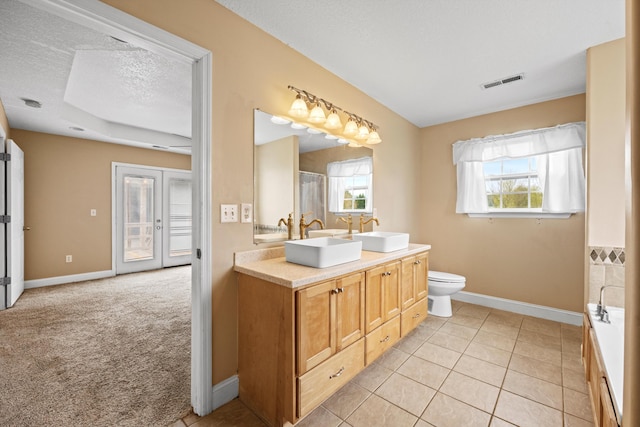 bathroom with a wealth of natural light, a textured ceiling, tile patterned floors, and toilet