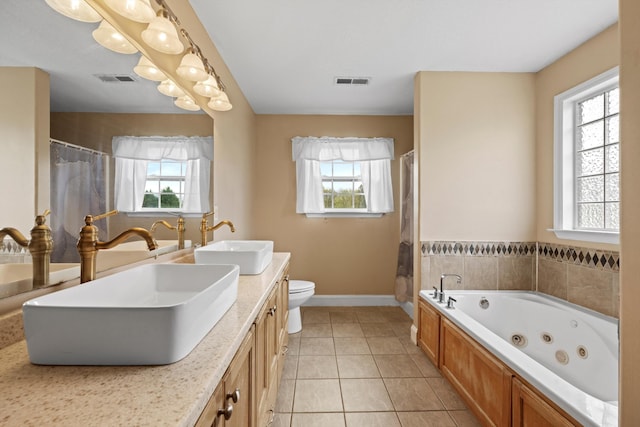 bathroom with a washtub, vanity, tile patterned floors, and toilet