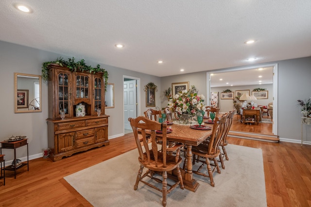 dining area with a textured ceiling and light hardwood / wood-style flooring