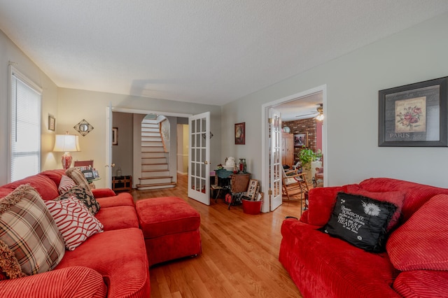 living room featuring french doors, a textured ceiling, light hardwood / wood-style floors, and ceiling fan