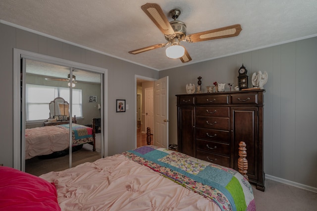 carpeted bedroom featuring a closet, ceiling fan, ornamental molding, and a textured ceiling