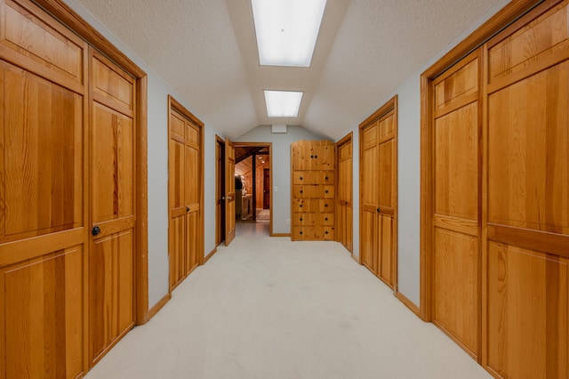 corridor featuring light carpet, a textured ceiling, and lofted ceiling