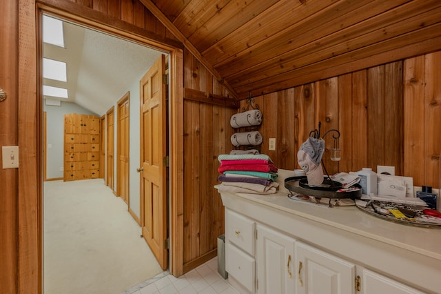 bathroom featuring vanity, wooden walls, and vaulted ceiling