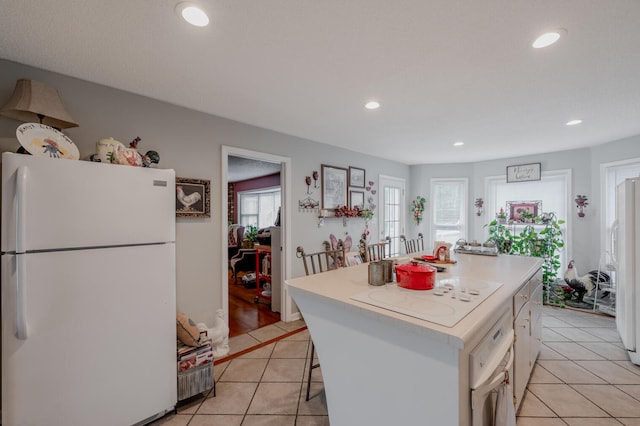 kitchen featuring white appliances, a healthy amount of sunlight, a kitchen island, and a kitchen breakfast bar