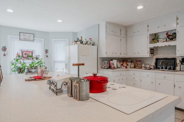 kitchen with white cabinetry, sink, and white refrigerator with ice dispenser