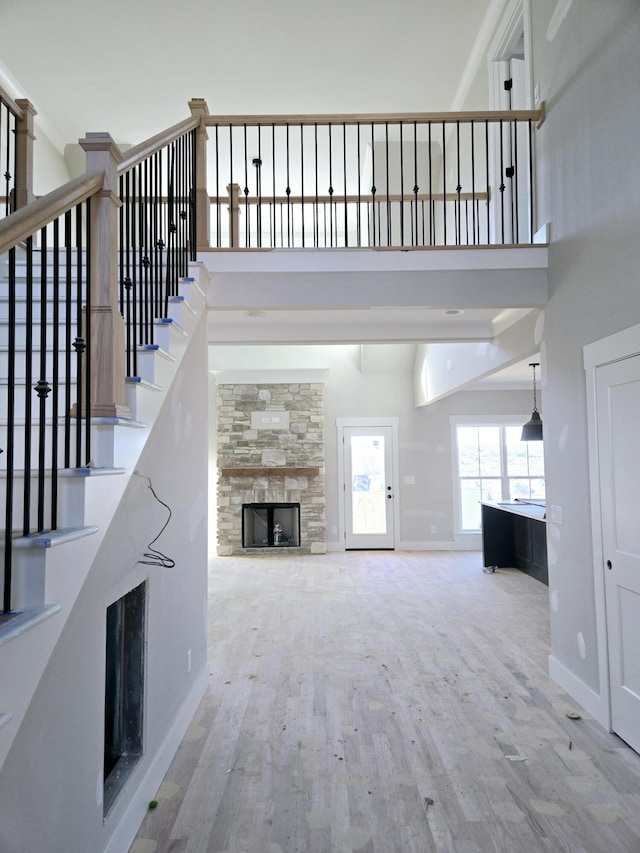 unfurnished living room featuring hardwood / wood-style flooring, a towering ceiling, and a fireplace