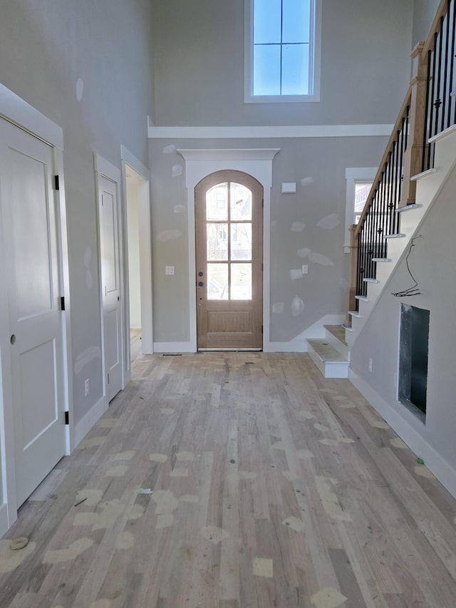 foyer entrance featuring a towering ceiling and light wood-type flooring