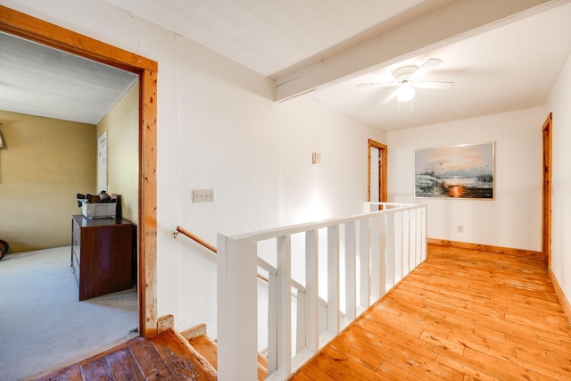 corridor with beam ceiling and light wood-type flooring