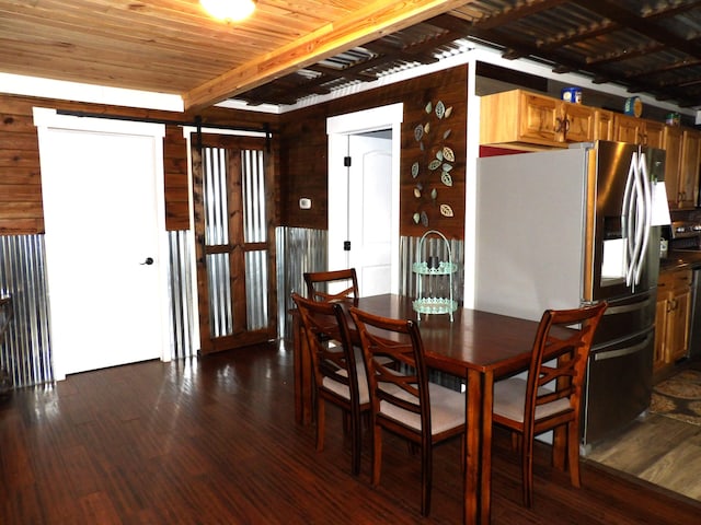 dining space featuring a barn door, dark hardwood / wood-style floors, and wood ceiling