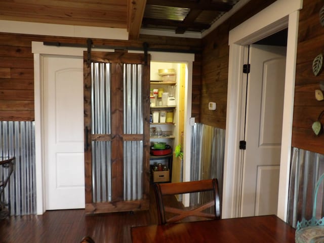 interior space featuring wood walls, beam ceiling, and a barn door