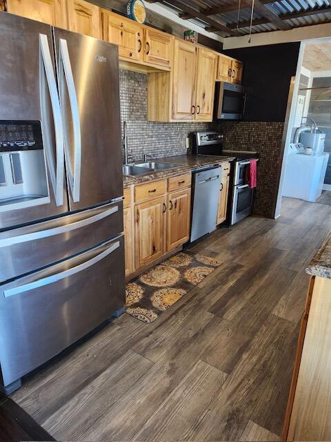 kitchen with dark wood-type flooring, appliances with stainless steel finishes, sink, and tasteful backsplash