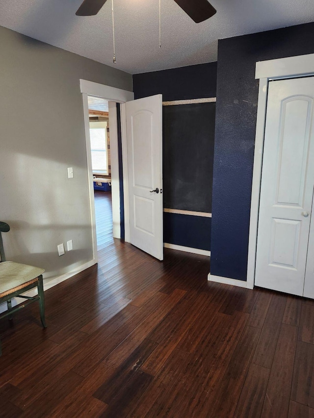 unfurnished bedroom featuring a textured ceiling, ceiling fan, and dark hardwood / wood-style floors