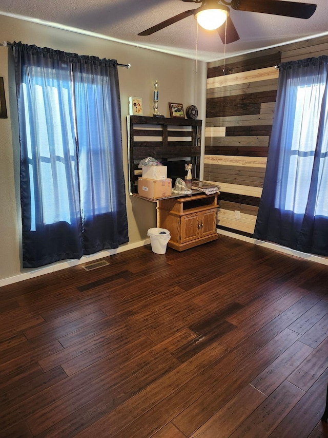 empty room featuring ceiling fan, dark wood-type flooring, and a textured ceiling