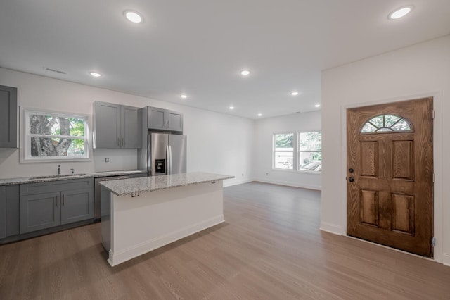 kitchen featuring light hardwood / wood-style flooring, gray cabinets, stainless steel refrigerator with ice dispenser, and a kitchen island