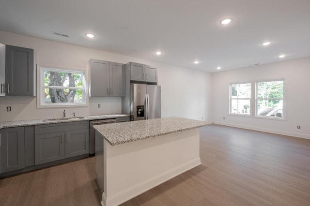 kitchen with wood-type flooring, gray cabinets, appliances with stainless steel finishes, and plenty of natural light