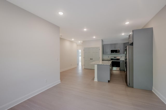 kitchen featuring gray cabinets, appliances with stainless steel finishes, light wood-type flooring, and a kitchen island