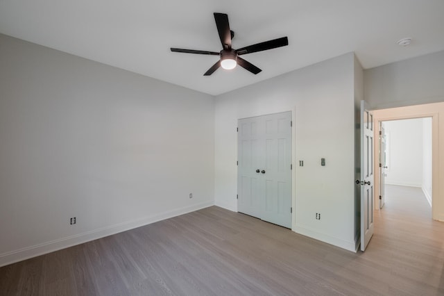 unfurnished bedroom featuring ceiling fan, a closet, and light hardwood / wood-style flooring