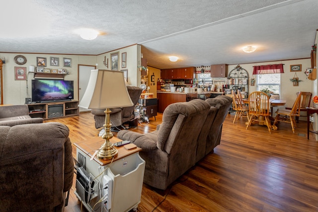 living room featuring wood-type flooring, ornamental molding, and a textured ceiling