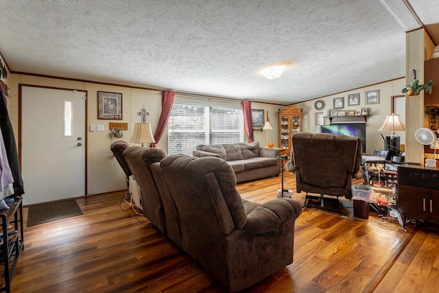 living room featuring vaulted ceiling, a textured ceiling, hardwood / wood-style floors, and ornamental molding