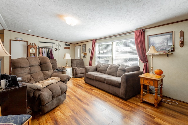 living room with ornamental molding, vaulted ceiling, hardwood / wood-style flooring, and a textured ceiling