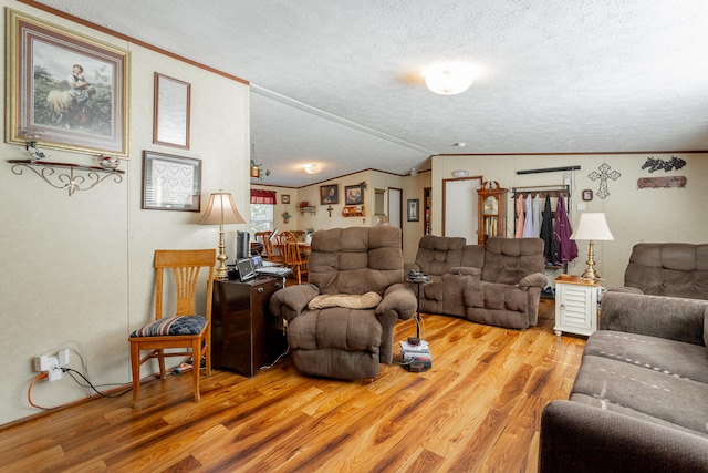 living room with light hardwood / wood-style floors, vaulted ceiling, ornamental molding, and a textured ceiling