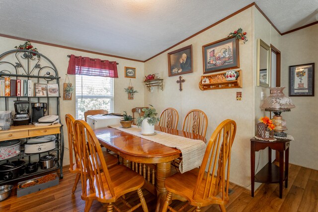 dining room with wood-type flooring, ornamental molding, and a textured ceiling