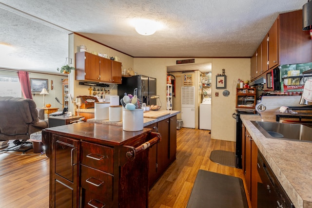 kitchen featuring a kitchen island, a textured ceiling, stainless steel fridge with ice dispenser, washer / dryer, and light hardwood / wood-style floors