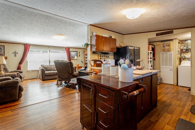 kitchen featuring stainless steel fridge, hardwood / wood-style flooring, washer / clothes dryer, and a textured ceiling