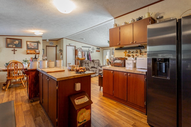 kitchen featuring ornamental molding, stainless steel refrigerator with ice dispenser, light hardwood / wood-style floors, and a textured ceiling