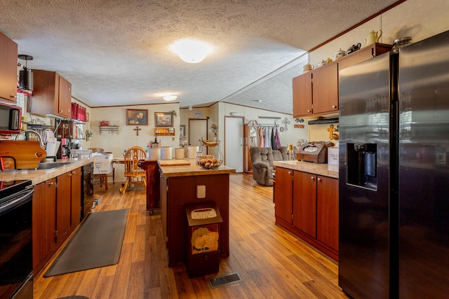 kitchen with refrigerator with ice dispenser, light hardwood / wood-style flooring, ornamental molding, and a textured ceiling