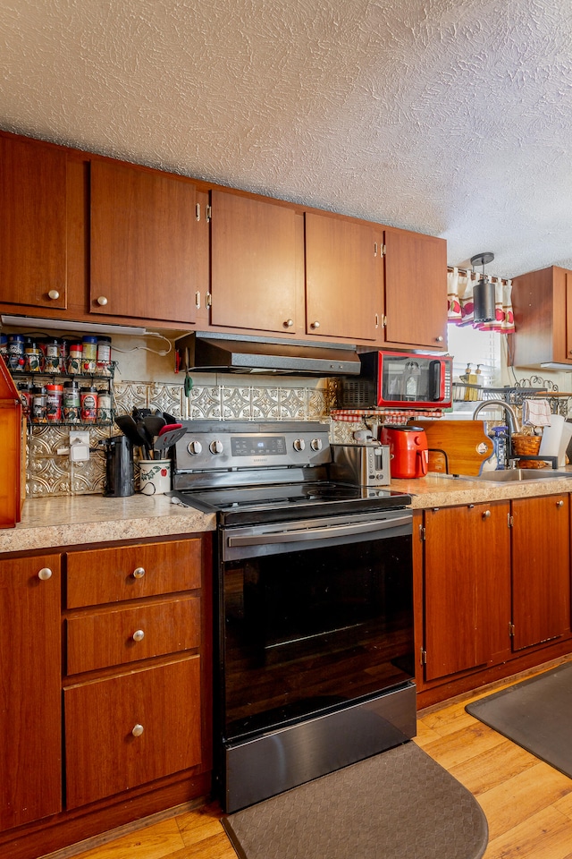 kitchen with light hardwood / wood-style floors, sink, a textured ceiling, and stainless steel electric range