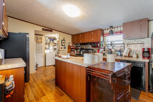 kitchen with dishwasher, light hardwood / wood-style floors, a textured ceiling, and washer / dryer