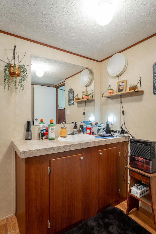 kitchen with crown molding, sink, light wood-type flooring, and a textured ceiling