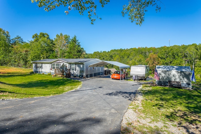 view of front facade featuring a front yard, a porch, a storage unit, and a carport