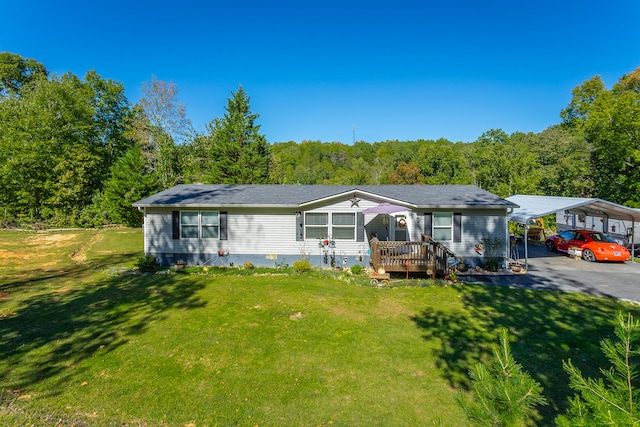 rear view of property with a carport, a yard, and a deck