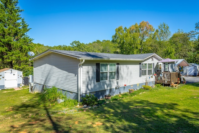 view of side of home featuring a deck, a yard, and a storage unit