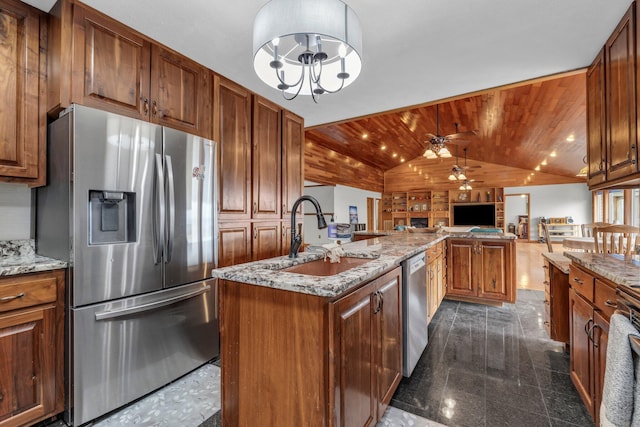 kitchen with light stone countertops, a kitchen island with sink, stainless steel appliances, sink, and vaulted ceiling