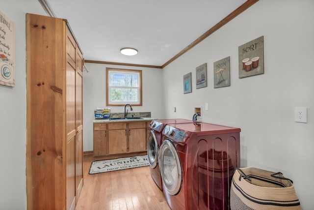 laundry room with separate washer and dryer, sink, light hardwood / wood-style flooring, crown molding, and cabinets