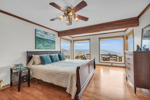 bedroom featuring light wood-type flooring, beamed ceiling, ceiling fan, crown molding, and a mountain view