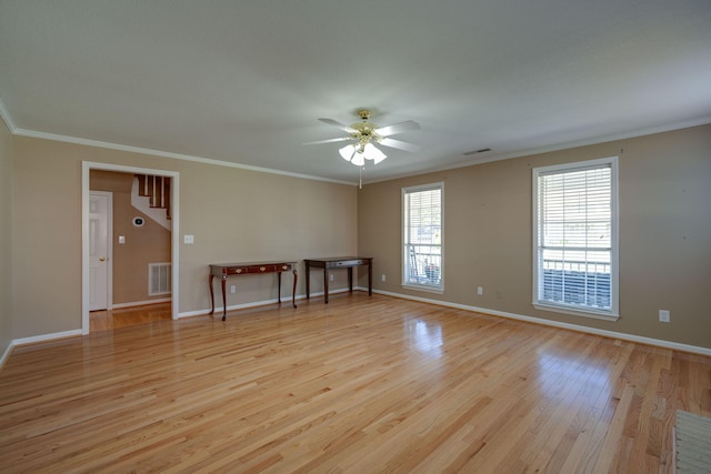 empty room with visible vents, light wood-style floors, crown molding, baseboards, and ceiling fan