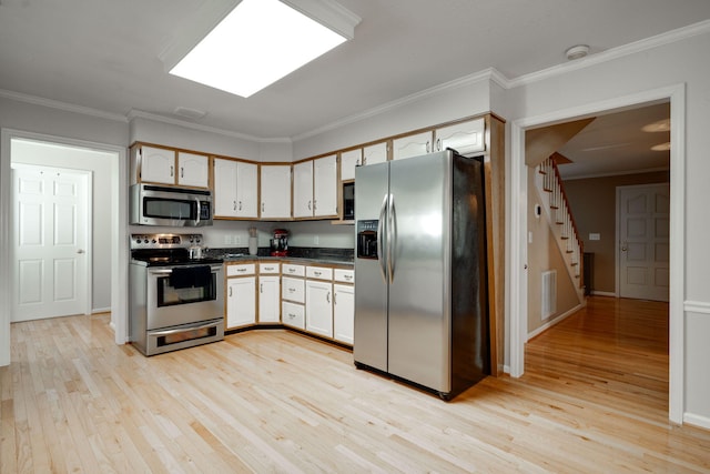 kitchen featuring visible vents, ornamental molding, appliances with stainless steel finishes, dark countertops, and light wood-type flooring