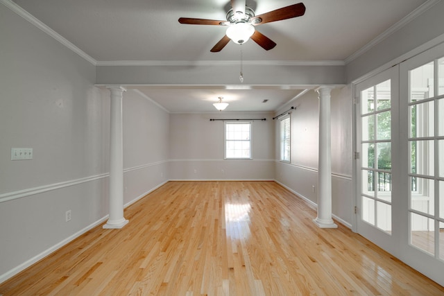 empty room featuring wood finished floors, baseboards, ornate columns, and ornamental molding