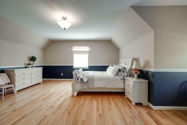 bedroom featuring light wood-type flooring, baseboards, and vaulted ceiling