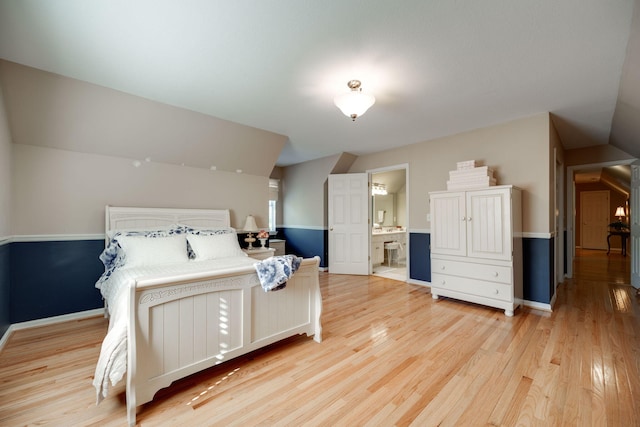 bedroom featuring ensuite bathroom, vaulted ceiling, and light wood-type flooring