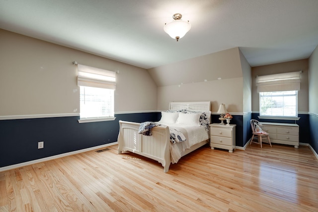 bedroom with light wood finished floors, visible vents, multiple windows, and baseboards