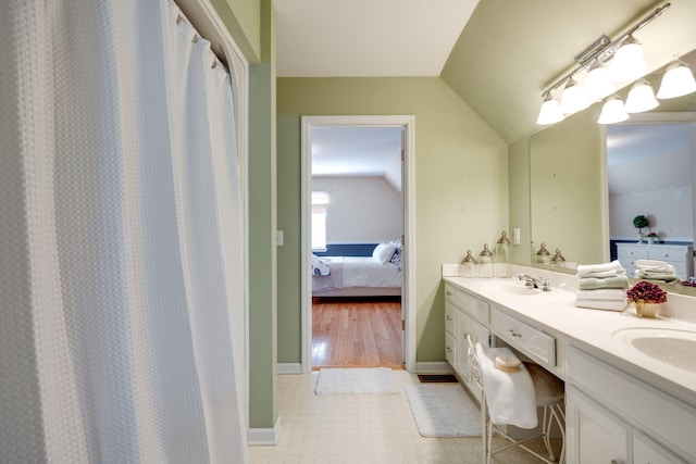 bathroom with a sink, lofted ceiling, ensuite bath, and double vanity