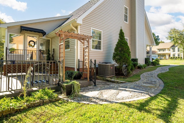 exterior space with central air condition unit, a lawn, and a pergola